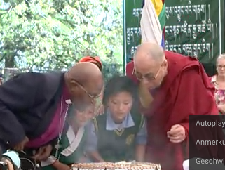 Tutu und zwei Kinder helfen dem Dalai Lama seine Geburtstagskerzen aus zu blasen